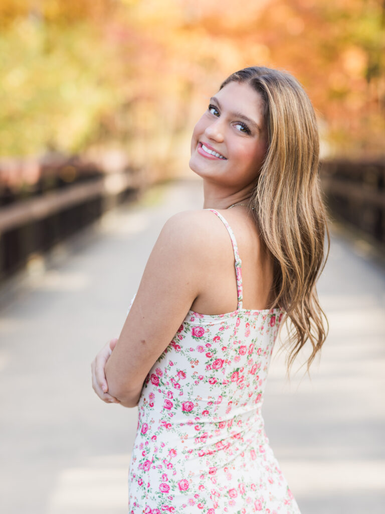 high school senior girl in pink floral dress posing at park for senior portraits Ohio senior photography