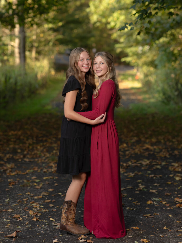 sisters posing for fall family photos in park Everett Covered Bridge in Peninsula