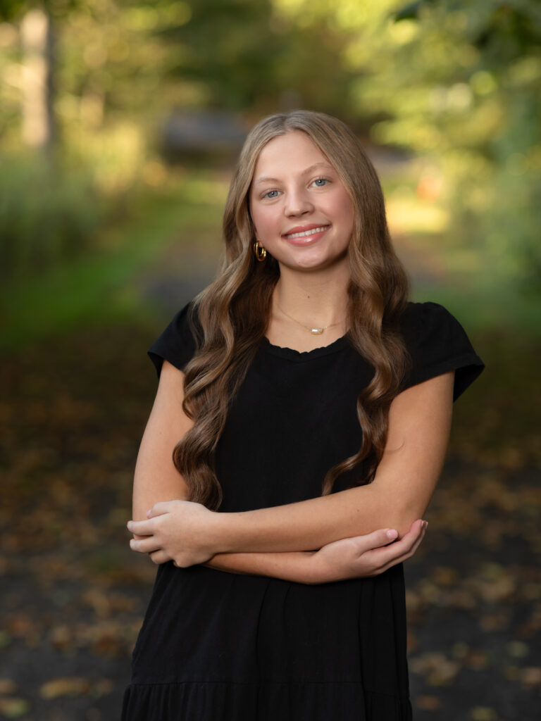 girl in black dress posing in park for fall family photos