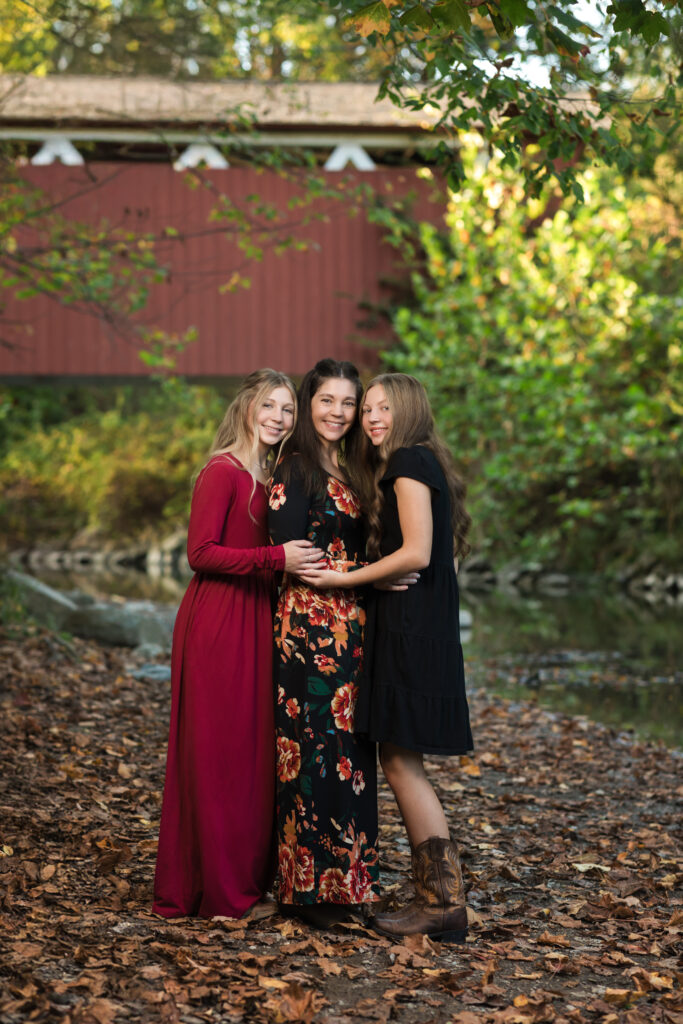 mother and two daughters posed in front of bridge for family photos Everett Covered Bridge in Peninsula