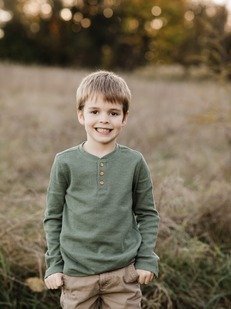 boy in green shirt posing for fall family photos Allardale Park Medina