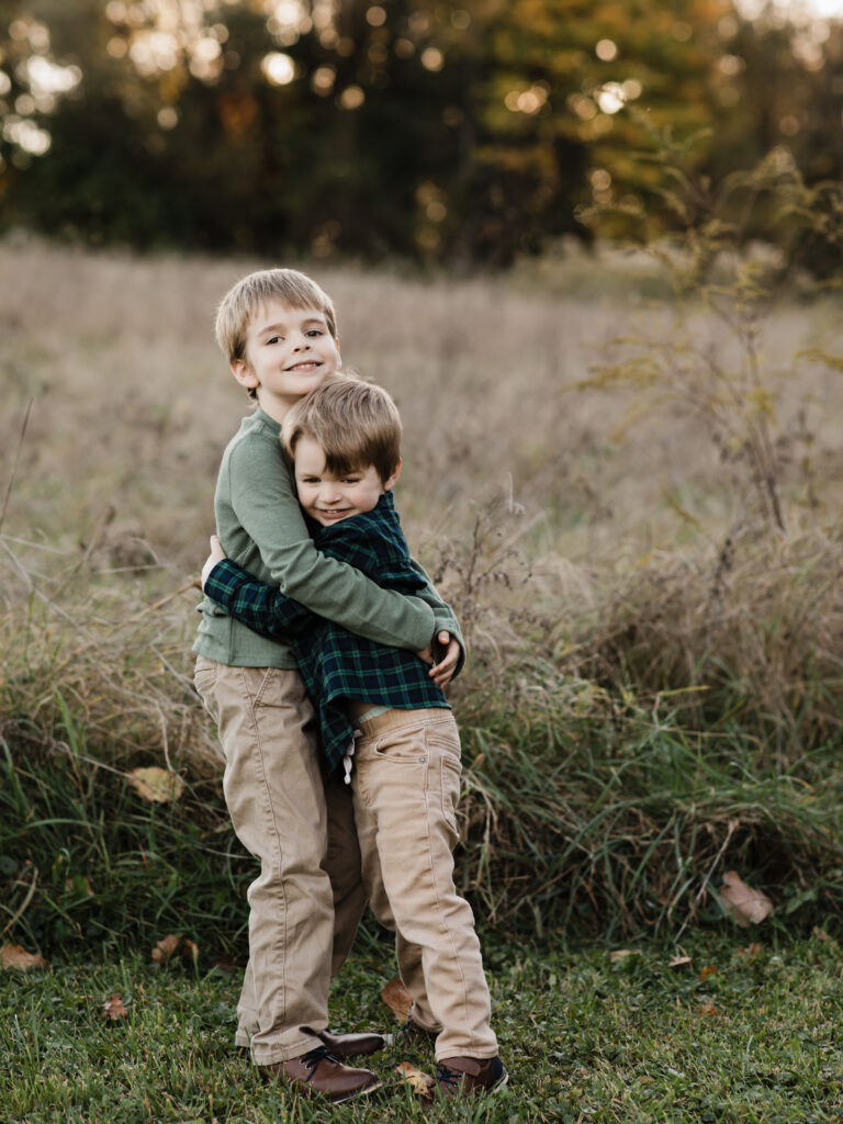 two brothers hugging in park for family photos 
