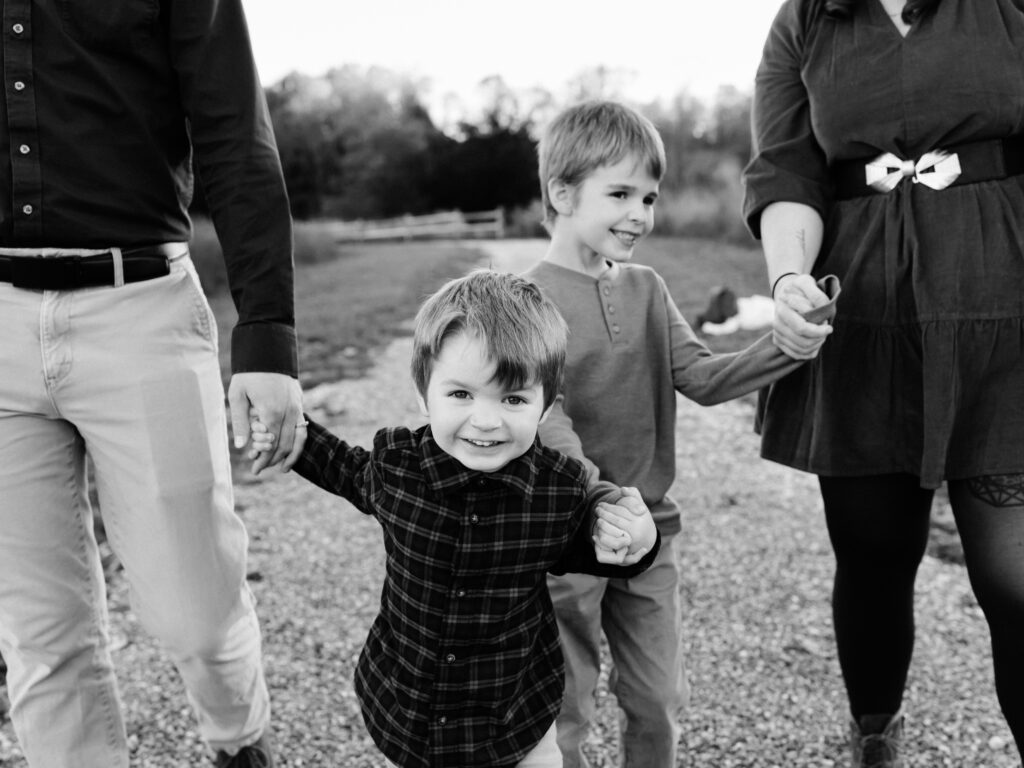 boys walking in park holding parents hands 