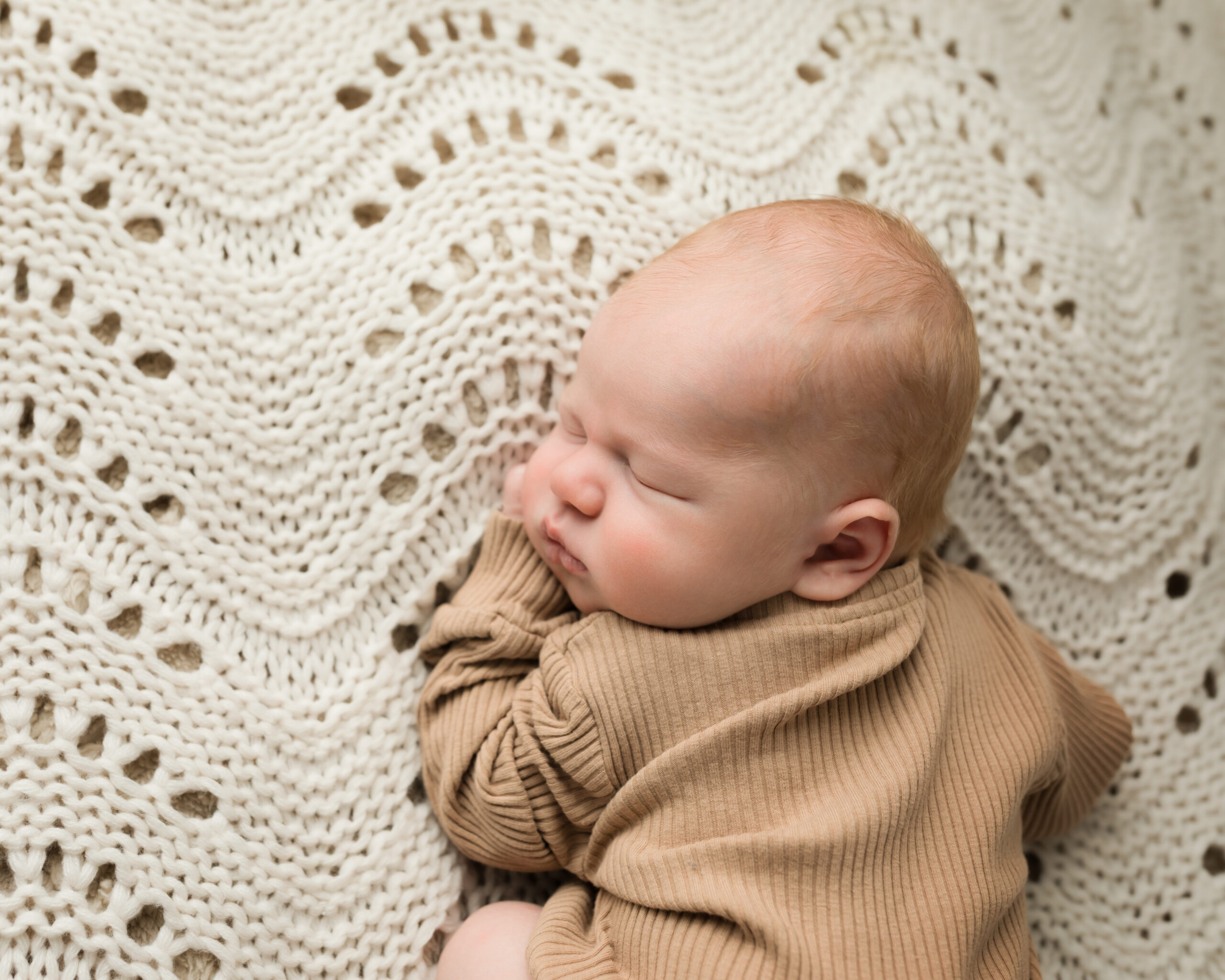 newborn baby boy posed on blanket in tan onesie for studio portraits Natural Bottoms Diaper Service