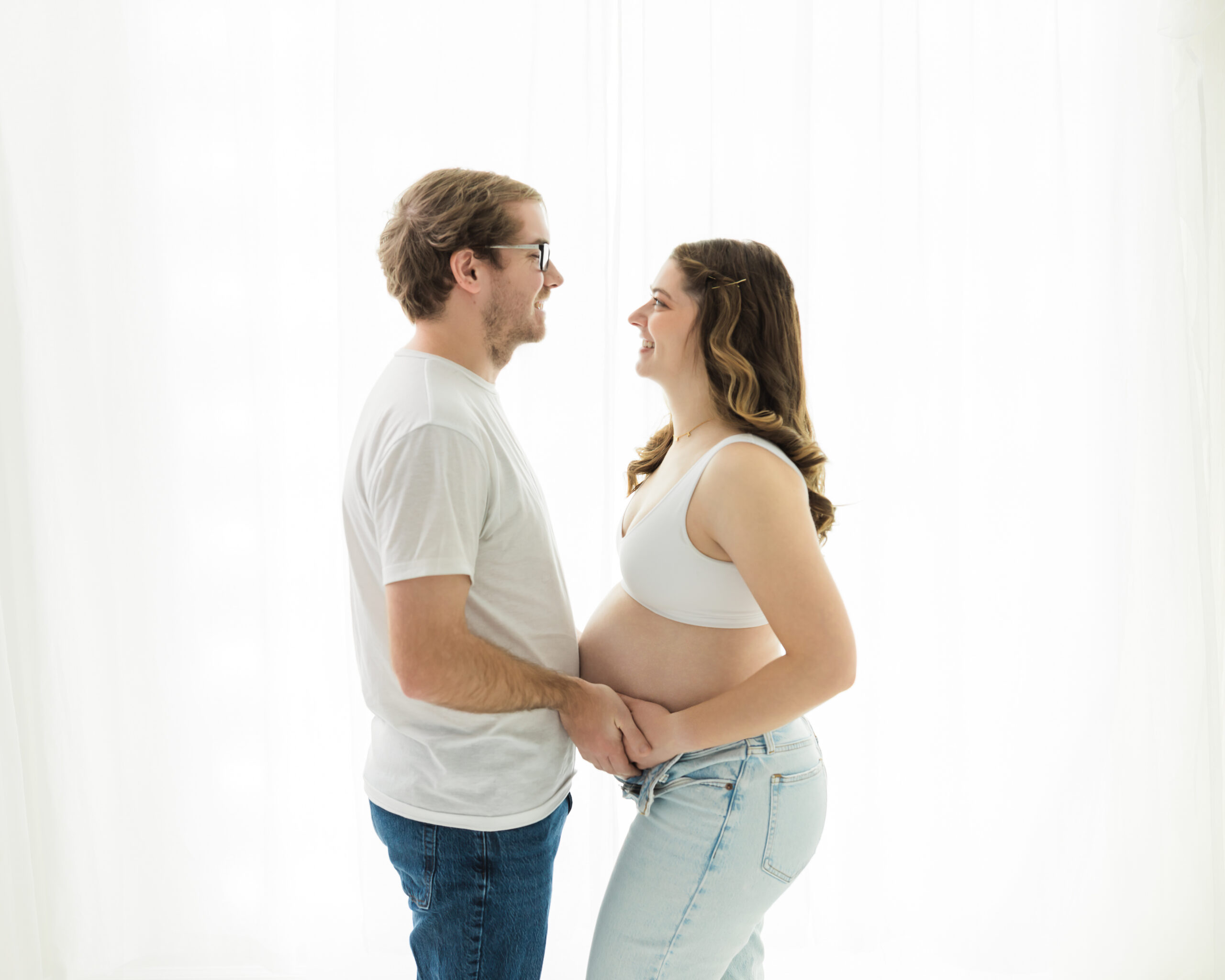 husband and pregnant wife in bra and jeans holding baby bump for maternity photos Urban Haven Cleveland