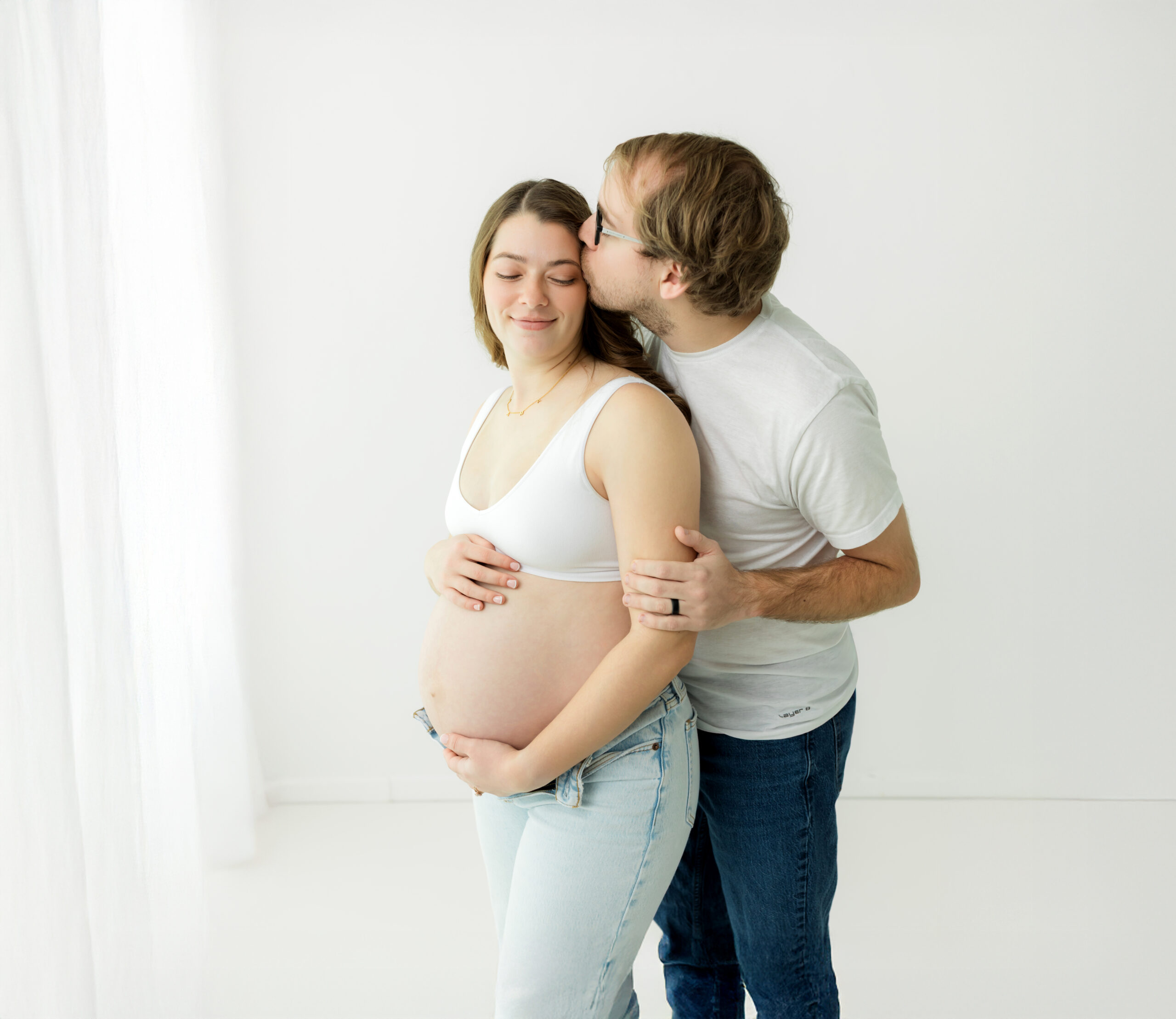 husband and pregnant wife in bra and jeans holding baby bump for maternity photos Prenatal Yoga Akron