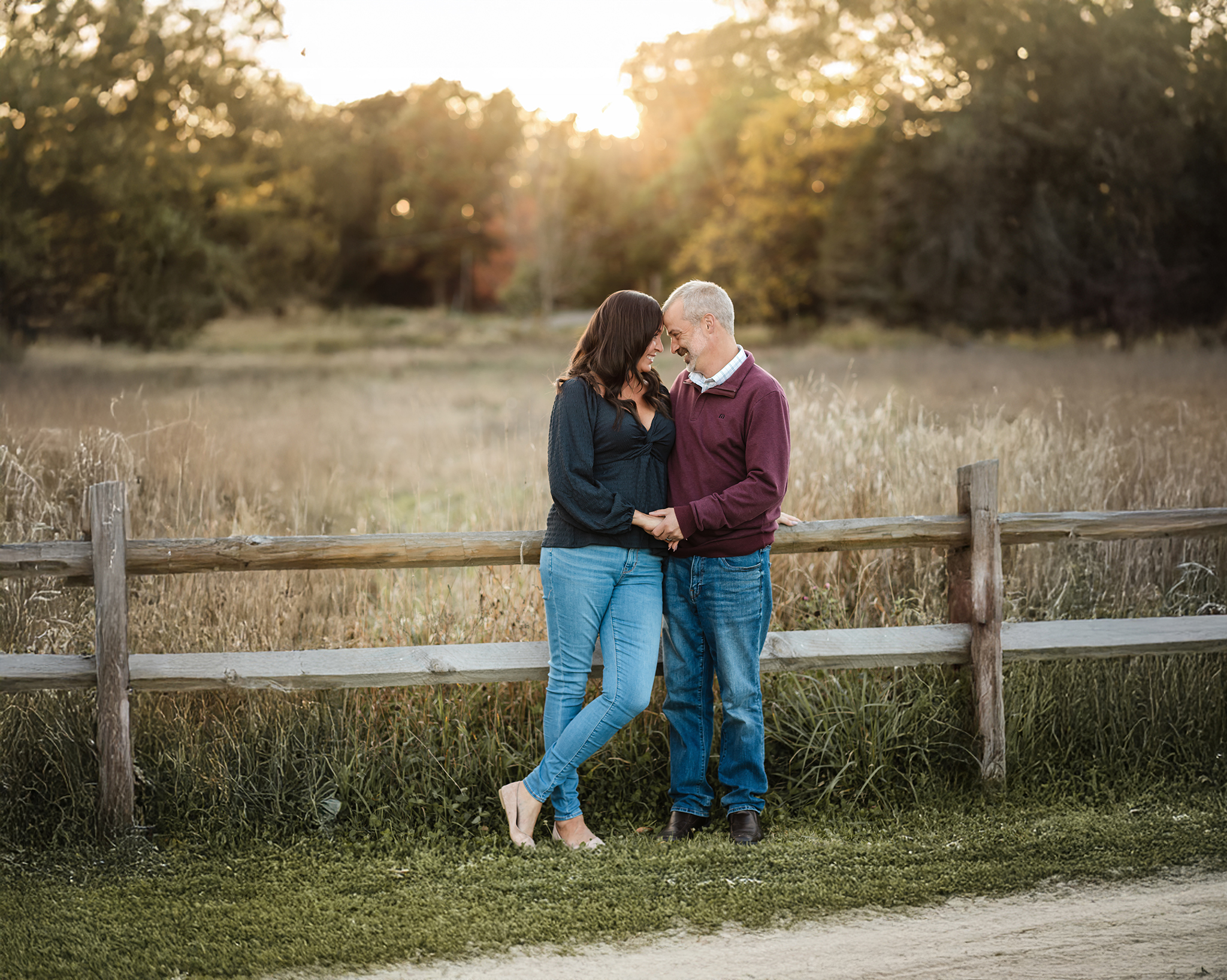 husband and wife posing against fence in field for family photos Spas in Fairlawn Ohio
