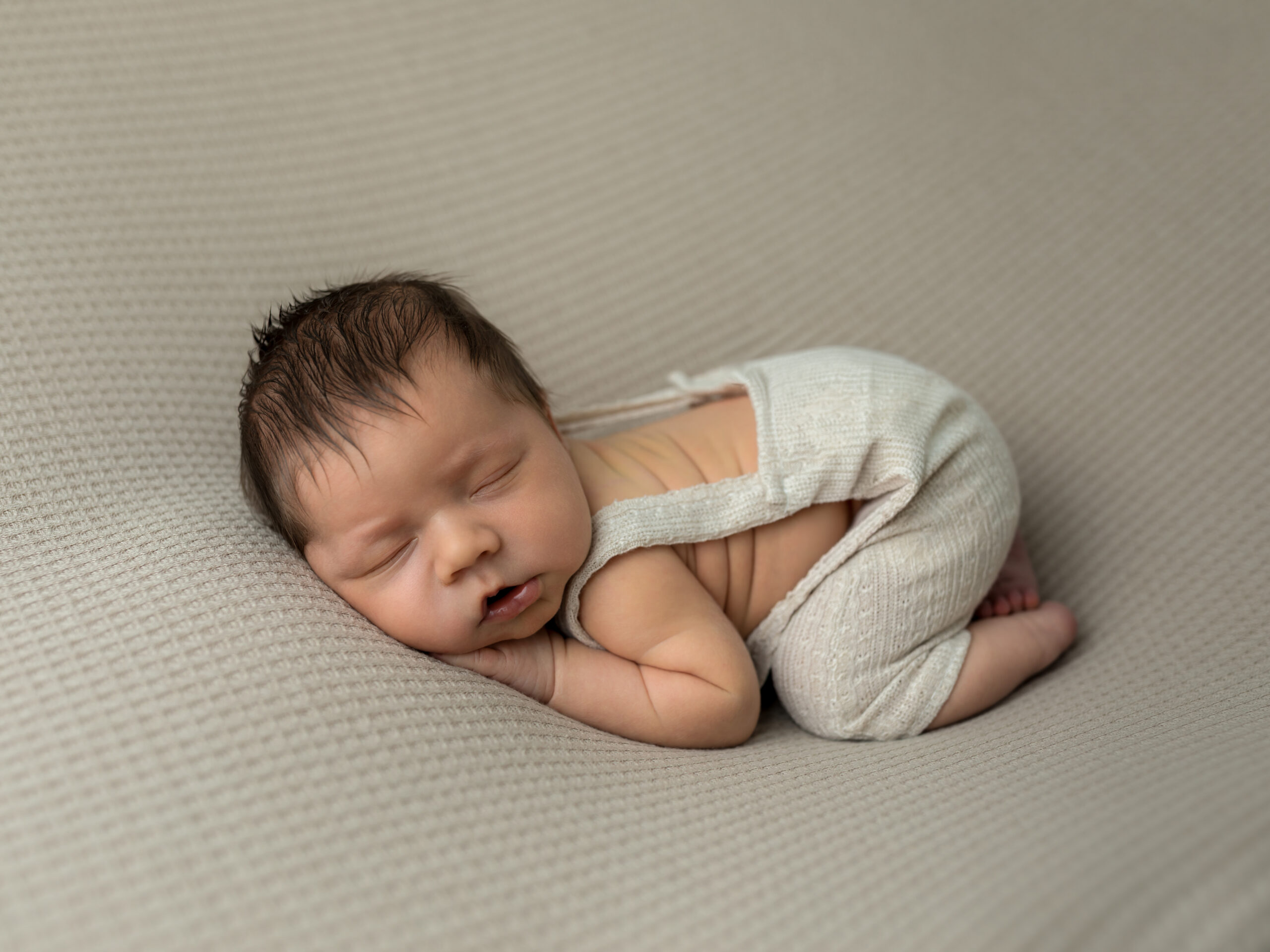 newborn baby boy in beige overalls posed on fabric Best Pediatricians in Cleveland Ohio