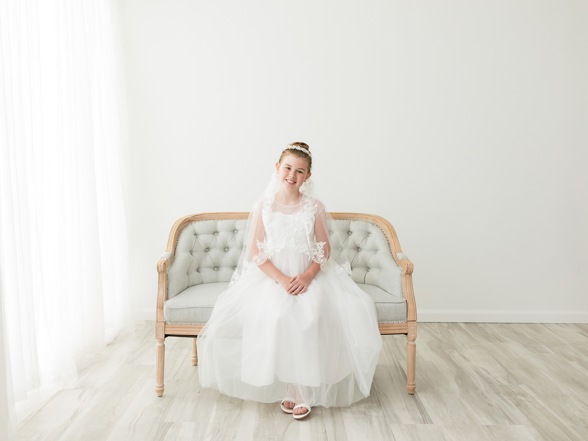 girl in fisrt communion dress sitting on settee for photoshoot Party Rentals Cleveland Ohio